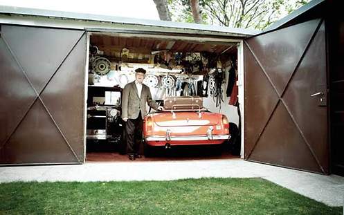 Das Bild zeigt einen Mann mit seinem Auto in einer Garage, die versichert ist. 