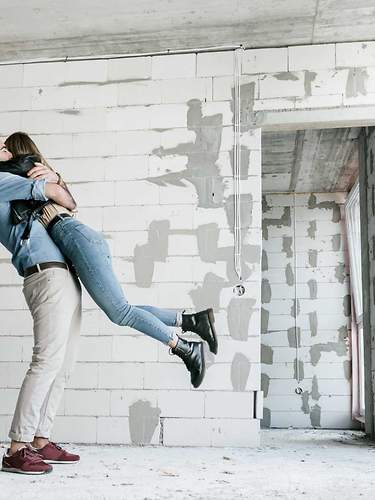 Ein Paar umarmt sich glücklich in ihrem Neubau, da es eine Baugenehmigung erhalten hat.