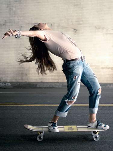 Das Bild zeigt eine junge Frau auf dem Skateboard