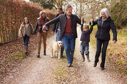 Glückliche Großeltern mit abgeschlossener Sterbegeldversicherung gehen mit ihrer Familie spazieren.
