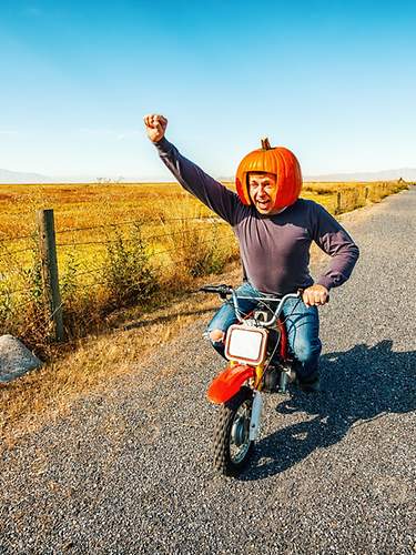 Mann mit Kürbis auf Motorrad.